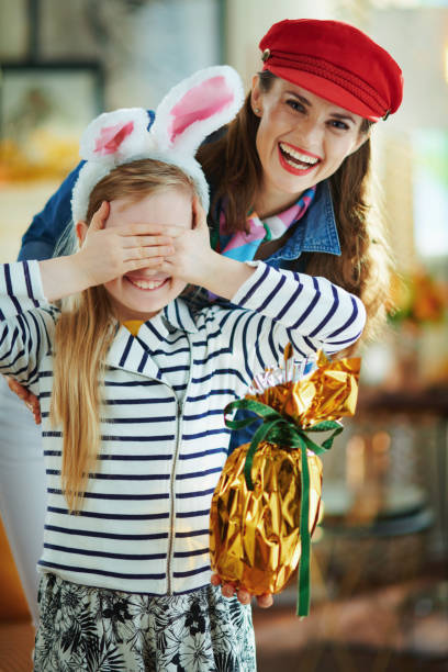 istock mother presenting easter egg to daughter in easter bunny ears 1213856143