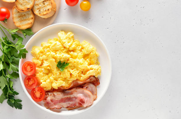 huevos revueltos, tocino frito y tomates en el plato - omelet bacon tomato fruit fotografías e imágenes de stock