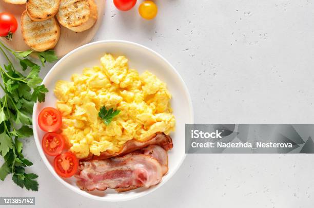 Plate with scrambled egg and bacon on white background Stock Photo - Alamy