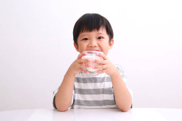 istock Cute Boy Holding Milk Glass Against White Background 1213859381