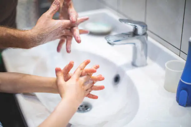 Photo of Father teaching son to wash hands