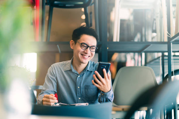 smart confidence asian startup entrepreneur business owner businessman smile hand use smartphone woking in office background - chino oriental fotos fotografías e imágenes de stock