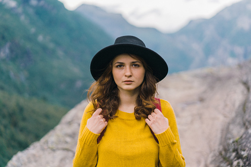 Portrait of young Caucasian  woman in yellow sweater and in  hat looking at camera