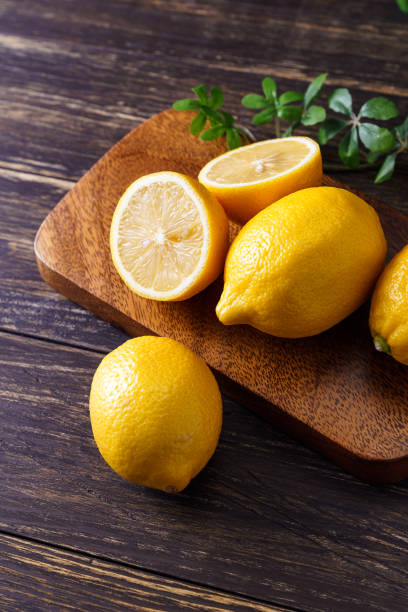 Sliced lemon fruit isolated on wooden background Sliced lemon fruit isolated on wooden background vibrant color lifestyles vertical close up stock pictures, royalty-free photos & images