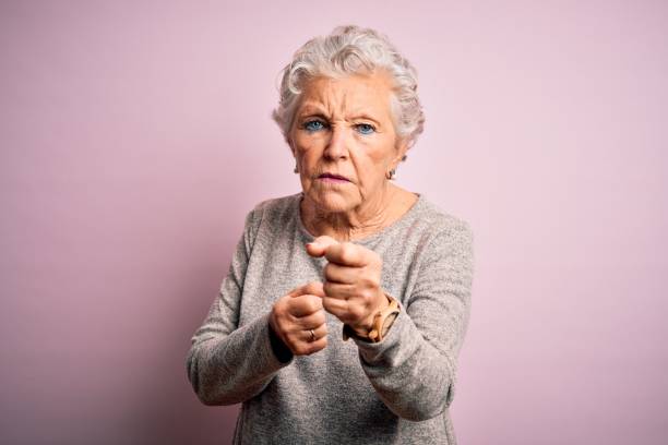 senior schöne frau trägt lässige t-shirt stehen dantinen rosa hintergrund bereit, mit faust verteidigung geste zu kämpfen, wütend und verärgert gesicht, angst vor problem - human fist stock-fotos und bilder