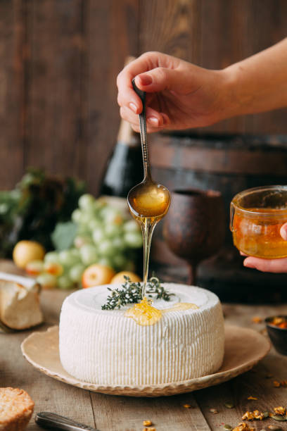 istock Curd cheese is watered with honey. The chef's hands prepare cheese. A large white round cheese on a plate. 1213866963