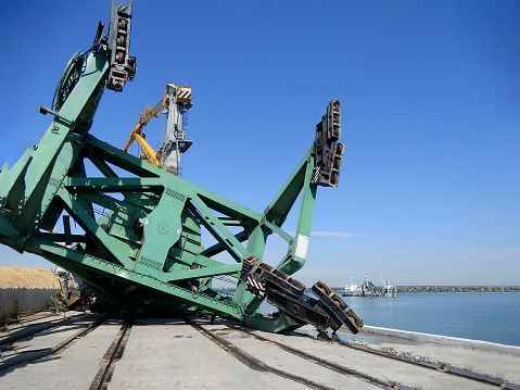 Harbor Crane collapse. Fallen port crane after a strong storm. A large-capacity harbor crane lies on the pier. The process of investigating an incident at a commercial port.