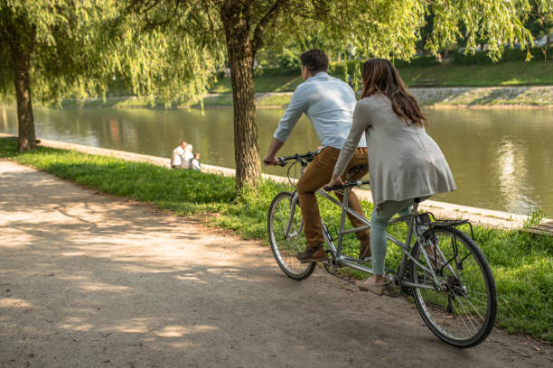 istock Couple riding a tandem bicycle on a river bank 1213868639