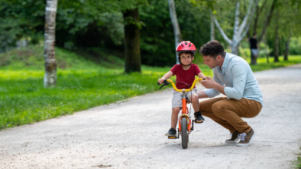 istock Father assisting his son with learning to ride a bicycle 1213868654