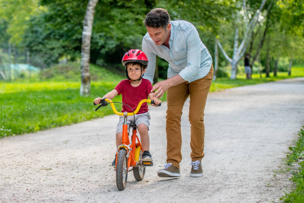 istock Father assisting son with learning to ride a bicycle 1213868660