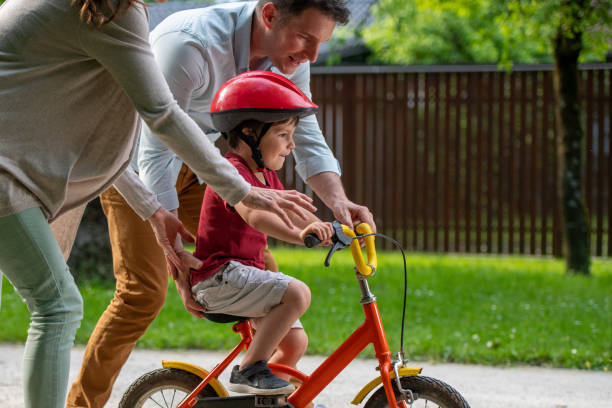 istock Mother and father assisting son in learning to ride a bicycle 1213868661