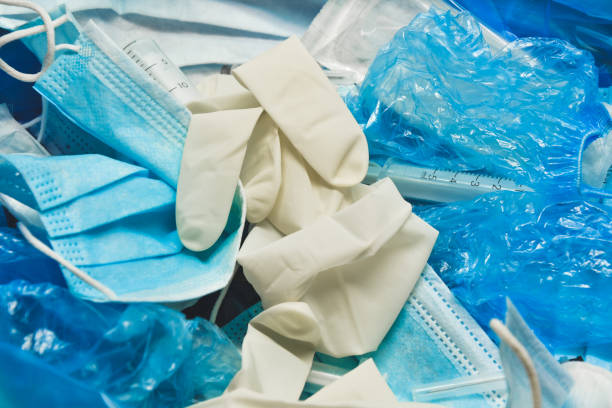 Medical trash. Coronavirus protection equipment in medical waste bin. Used face masks and sterile gloves. Doctor uniform for patient treatment in hospital. Prevention the spread of COVID-19. stock photo