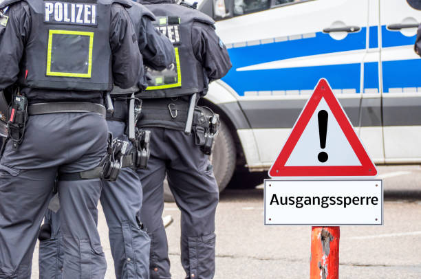 istock Police curfew warning sign in german background 1213870425
