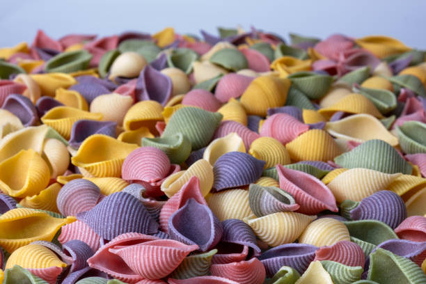 istock Pasta Conchiglie Rigate, mix of colorful uncooked shells with spinach and tomatoes. Textured Italian food background concept. Top view flat lay 1213871655