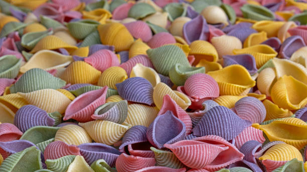 istock Pasta Conchiglie Rigate, mix of colorful uncooked shells with spinach and tomatoes. Textured Italian food background concept. Top view flat lay 1213871807