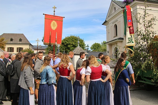 Mattsee, Austria- Sept. 22, 2019: At a parochial festivity in the countryside. Young People in traditional costumes in front of a church. Europe.