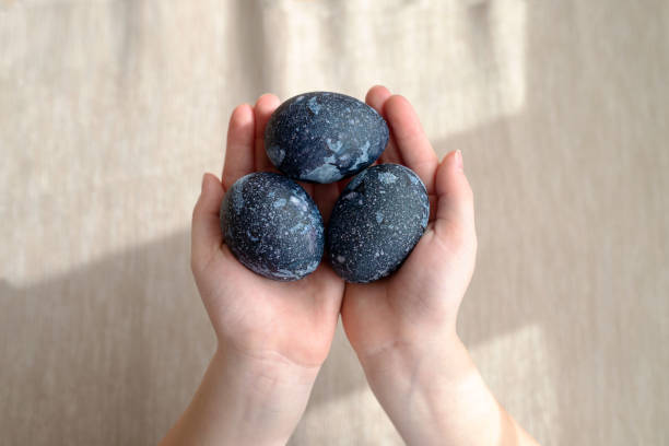 istock Hands holding cosmic dark blue with white dots painted easter eggs. Happy easter concept. 1213873808