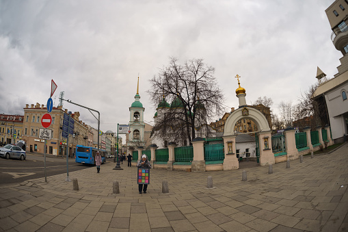 Moscow, Russia - March  20, 2020: Fish-Eye. Cityscape in spring sunset. A few people on the street. Coronavirus Pandemic lifestyle of the big city. The capital of Russian Federation is alive.