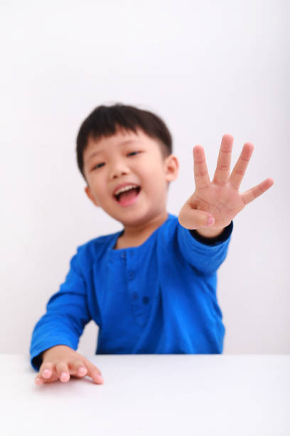 garçon asiatique comptant utilisant des doigts - elementary age focus on foreground indoors studio shot photos et images de collection