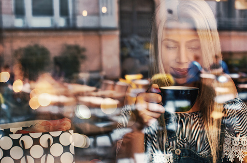 Young sad woman at coffee shop drinking coffee.