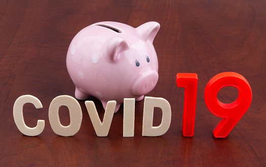 Save money in coronavirus covid-19 time concept. Piggy bank and word covid19 close up.