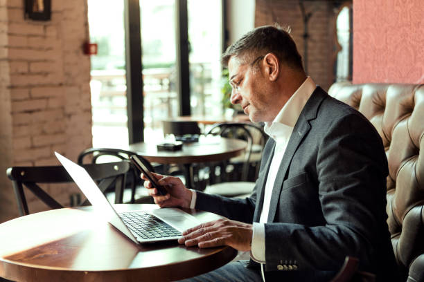 istock Businessman on a coffee break with laptop working looking at smart phone 1213877462