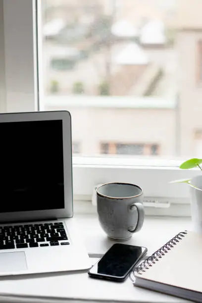 Photo of Office view with laptop, mobile phone, cup of coffee and notebook