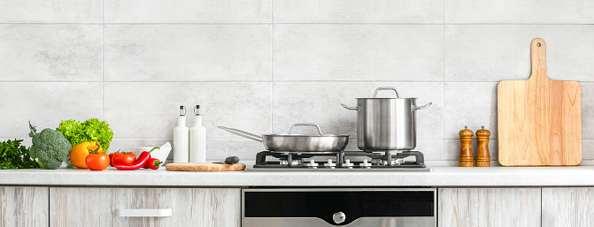 Fresh clean vegetables being put on a kitchen desk top, ready for cooking, front view of modern kitchen countertop with domestic culinary utensils on it, home healthy cooking concept banner