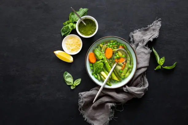 Detox vegetable soup with fresh asparagus and green peas, top down view
