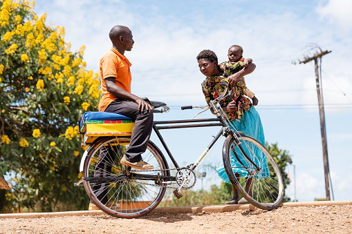 Mzuzu, Malawi - February 27, 2019:  Local people on the street market, man with bike and woman with child on back in Mzuzu, Malawi.