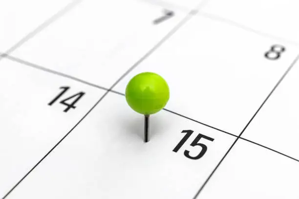 Green pinned pin in calendar on 15th day.