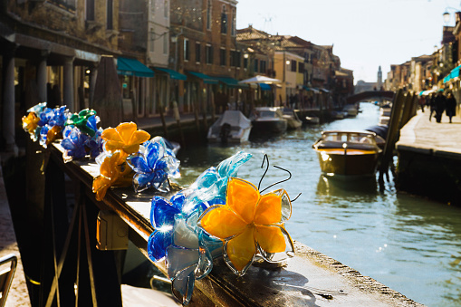 On Murano island, streets are decorated with crystal clear glass artifacts, which are glittering in Italian sunlight. The streets of course are waterways with boats.