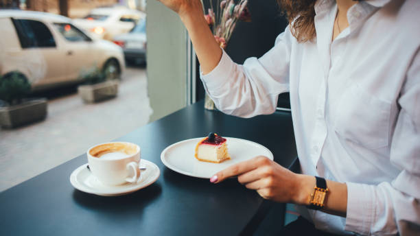 istock Young woman eating cheesecake drinking coffee 1213893173