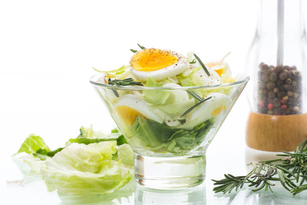 fresh spring salad with cabbage, lettuce and boiled eggs with rosemary and spices on a white background