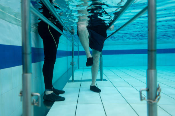 Senior man doing physical therapy in the water Senior man doing physical therapy in the water with the help of a physiotherapist - medical concepts hydrotherapy stock pictures, royalty-free photos & images