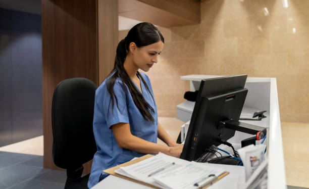 Nurse working on the computer at a nurse station Nurse working on the computer at a nurse station in the hospital - healthcare and medicine workers triage stock pictures, royalty-free photos & images