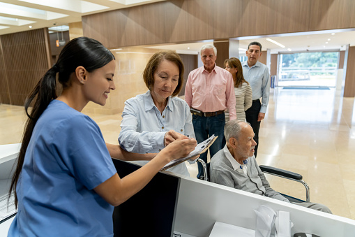 Senior woman registaring a patient at the hospital at the nurse station