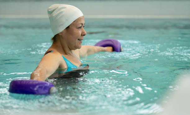 Adult woman in hydrotherapy doing exercises for her back Happy Latin American adult woman in hydrotherapy doing exercises for her back using free-weights hydrotherapy stock pictures, royalty-free photos & images