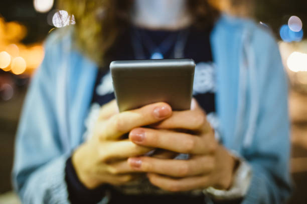istock Female hands holding mobile phone on street 1213906186