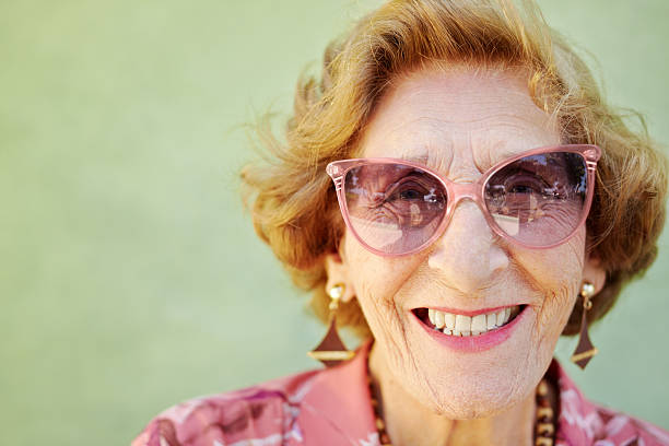 rosa envelhecido mulher com óculos sorrindo para a câmera - pink glasses - fotografias e filmes do acervo