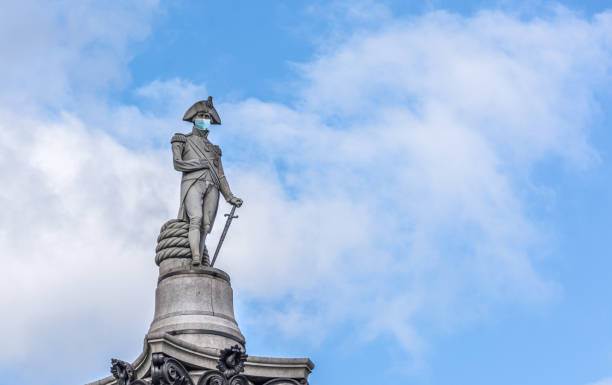 statua dell'ammiraglio nelson a londra con una maschera chirurgica - il monumento di nelson foto e immagini stock