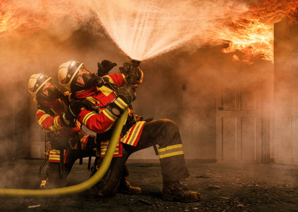 two firefighters in a burning house - fire hose imagens e fotografias de stock
