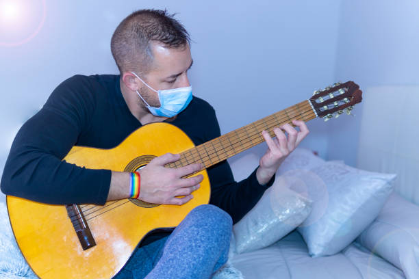 istock young man playing guitar with gay pride bracelet 1213913934