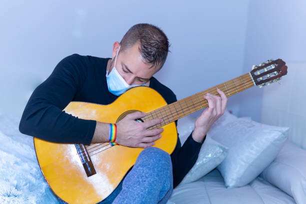 istock young man playing guitar with gay pride bracelet 1213913937