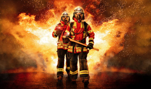 Two firefighters go through the fire Two firefighters run through the fire under respiratory protection and heavy equipment to save people. fire station stock pictures, royalty-free photos & images