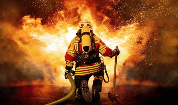 A firefighter kneels before the fire A firefighter faces a big task. He is equipped with heavy respiratory protection and wears protective equipment that protects him from the heat and flames. extinguishing stock pictures, royalty-free photos & images