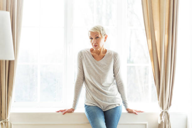 istock Cheerless senior female sitting on the sill 1213917955