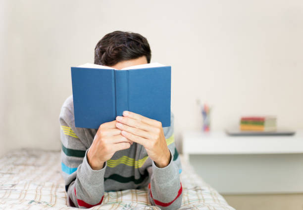 istock young man reading a book in his bedroom. 1213918150