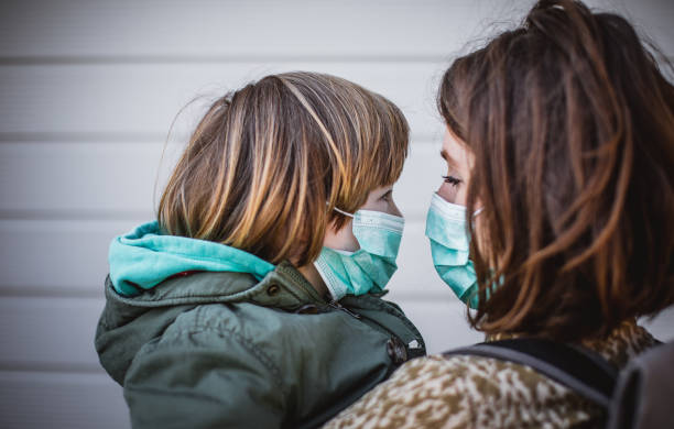 istock Mother with son on the street wearing protective mask 1213923680