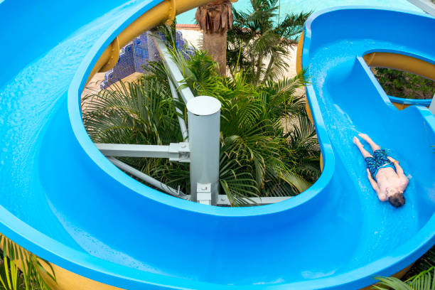 Boy Sliding Down a Blue Waterslide This picture shows a top view perspective of a boy sliding down a blue waterslide. top of water slide photos stock pictures, royalty-free photos & images
